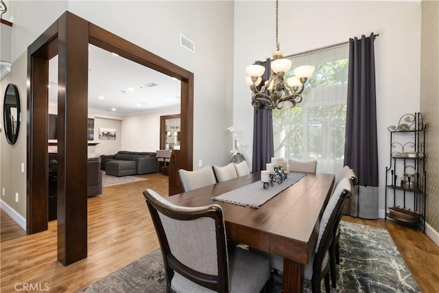 dining space with wood-type flooring, crown molding, and an inviting chandelier