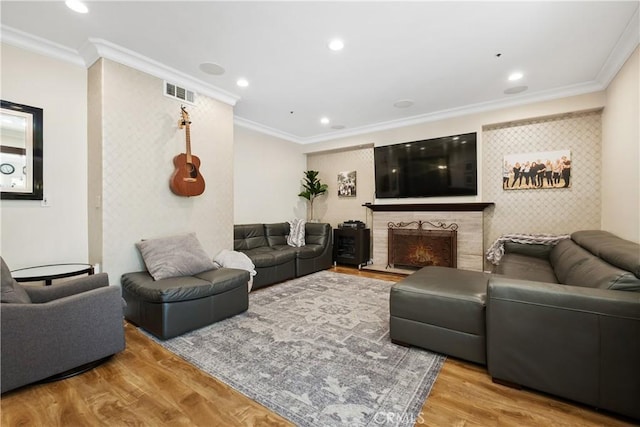 living room with hardwood / wood-style flooring, crown molding, and a tile fireplace