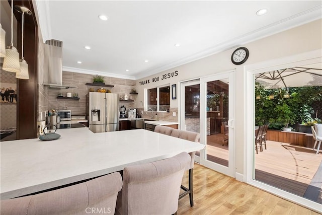 kitchen featuring stainless steel fridge with ice dispenser, island range hood, sink, a kitchen bar, and kitchen peninsula