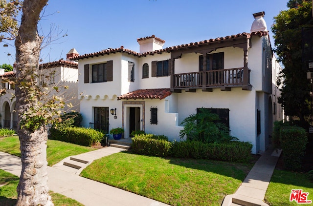 mediterranean / spanish-style home with a front yard and a balcony