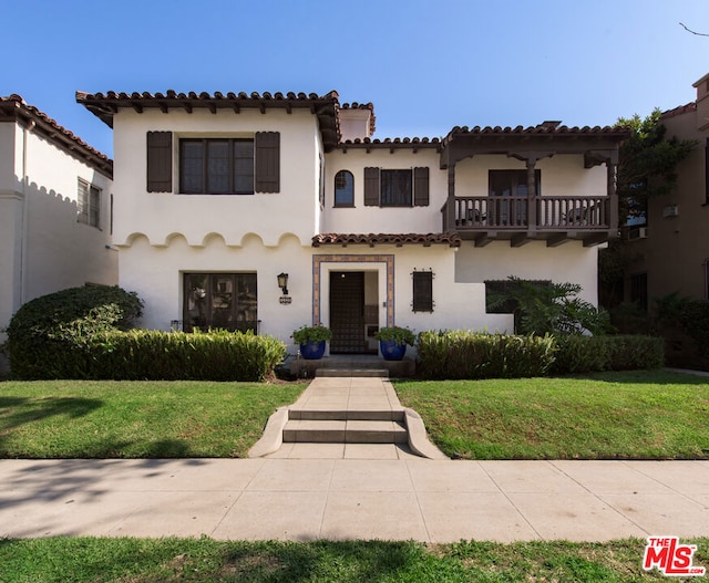 mediterranean / spanish-style house featuring a balcony and a front lawn