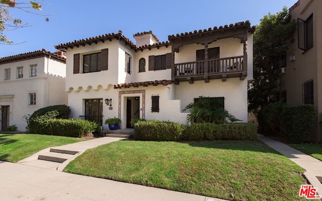 mediterranean / spanish-style home featuring a balcony and a front lawn