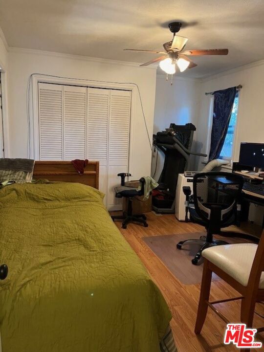 bedroom featuring ornamental molding, hardwood / wood-style flooring, a closet, and ceiling fan