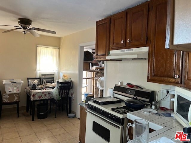 kitchen featuring ceiling fan, light tile patterned flooring, and white appliances