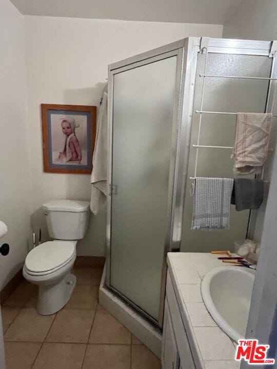 bathroom with vanity, toilet, tile patterned floors, and a shower with door