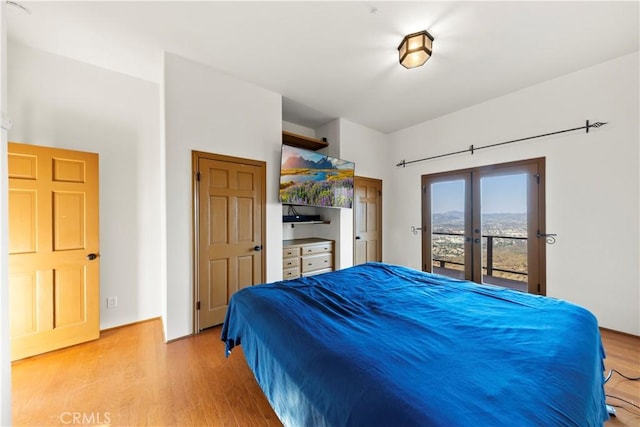 bedroom with access to outside, french doors, and light wood-type flooring