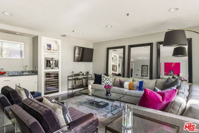 living room with built in features, a textured ceiling, hardwood / wood-style flooring, bar, and beverage cooler