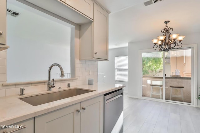 kitchen with sink, light stone counters, stainless steel dishwasher, decorative backsplash, and white cabinets