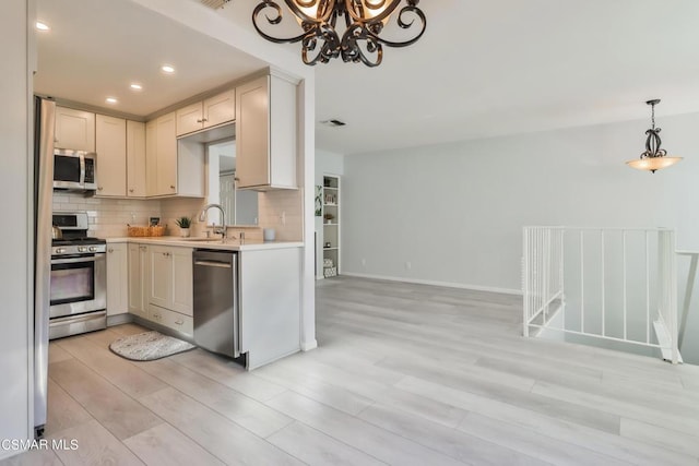 kitchen with pendant lighting, backsplash, sink, and appliances with stainless steel finishes