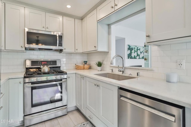 kitchen featuring sink, backsplash, stainless steel appliances, and white cabinets