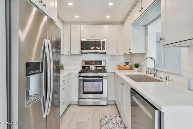 kitchen featuring appliances with stainless steel finishes, tasteful backsplash, sink, white cabinets, and light stone countertops