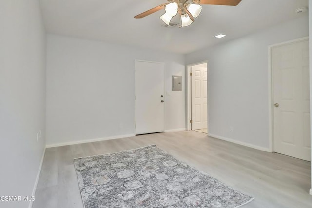 empty room featuring electric panel, ceiling fan, and light hardwood / wood-style flooring