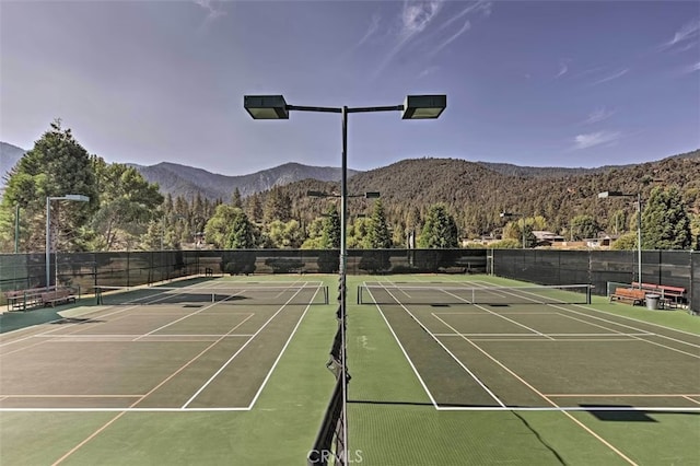 view of tennis court with basketball hoop and a mountain view