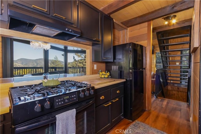 kitchen featuring black appliances, beam ceiling, a mountain view, hardwood / wood-style floors, and butcher block countertops