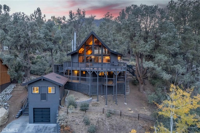 back house at dusk featuring a garage and a wooden deck