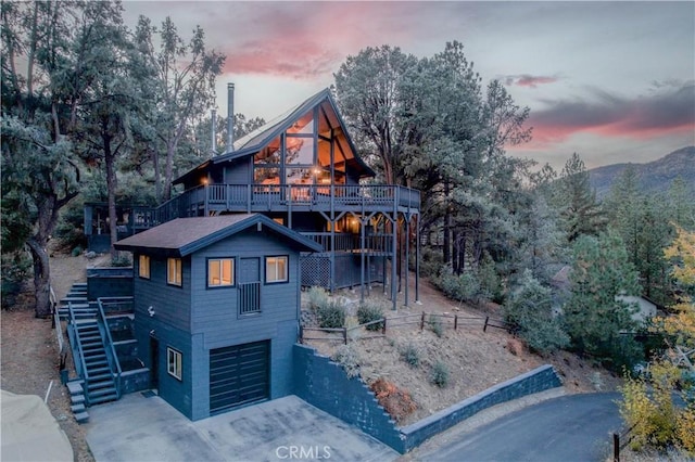 back house at dusk featuring a garage and a wooden deck