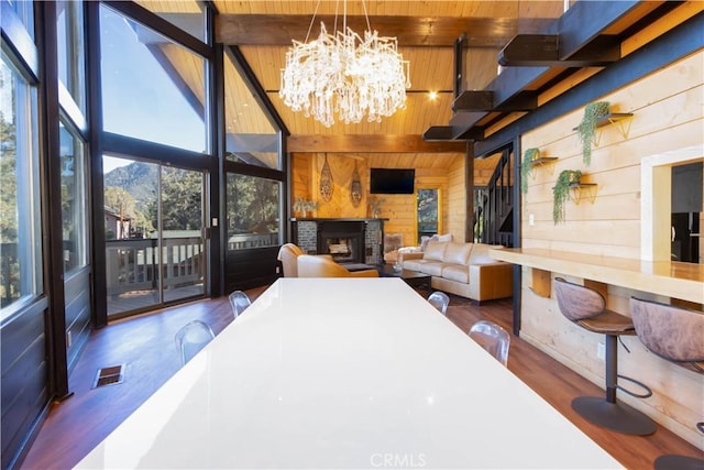 interior space with a brick fireplace, wooden walls, lofted ceiling with beams, wooden ceiling, and dark hardwood / wood-style floors