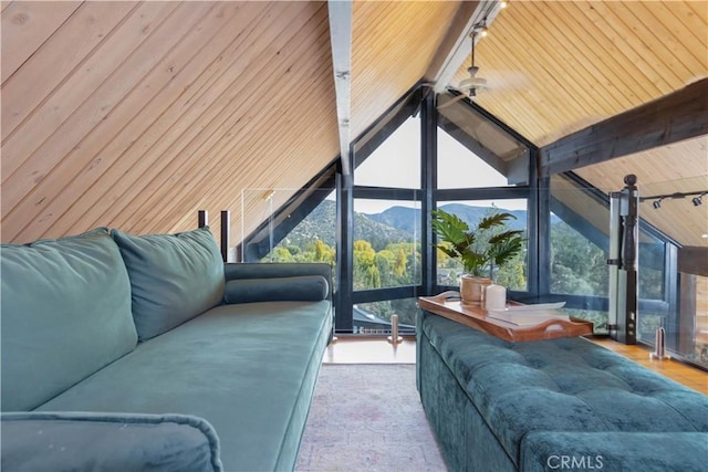 living room featuring a mountain view, rail lighting, lofted ceiling with beams, and a healthy amount of sunlight