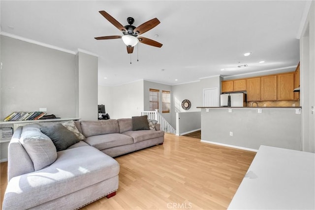 living room featuring light wood-type flooring, ceiling fan, and ornamental molding