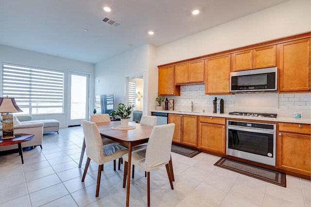 kitchen with sink, light tile patterned floors, stainless steel appliances, and tasteful backsplash