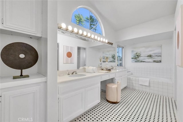 bathroom featuring vanity, tiled bath, and a healthy amount of sunlight