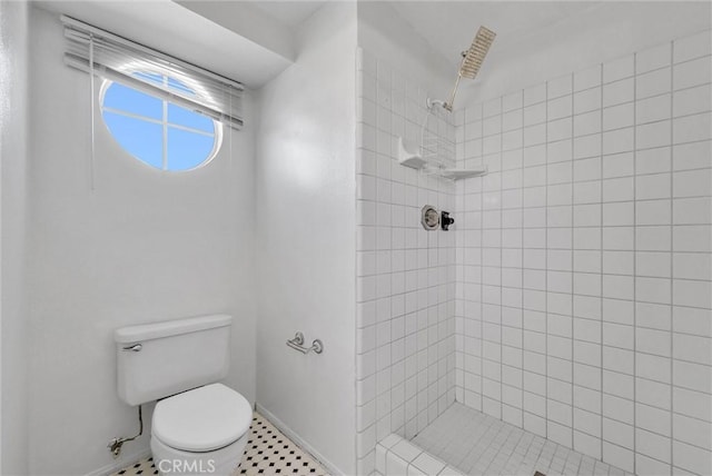 bathroom with tile patterned floors, toilet, and tiled shower