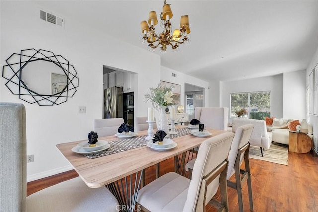 dining space with wood-type flooring and a notable chandelier