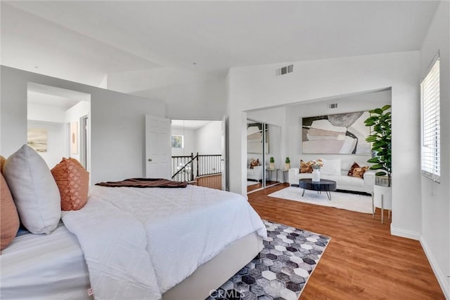 bedroom with hardwood / wood-style flooring, a closet, lofted ceiling, and multiple windows