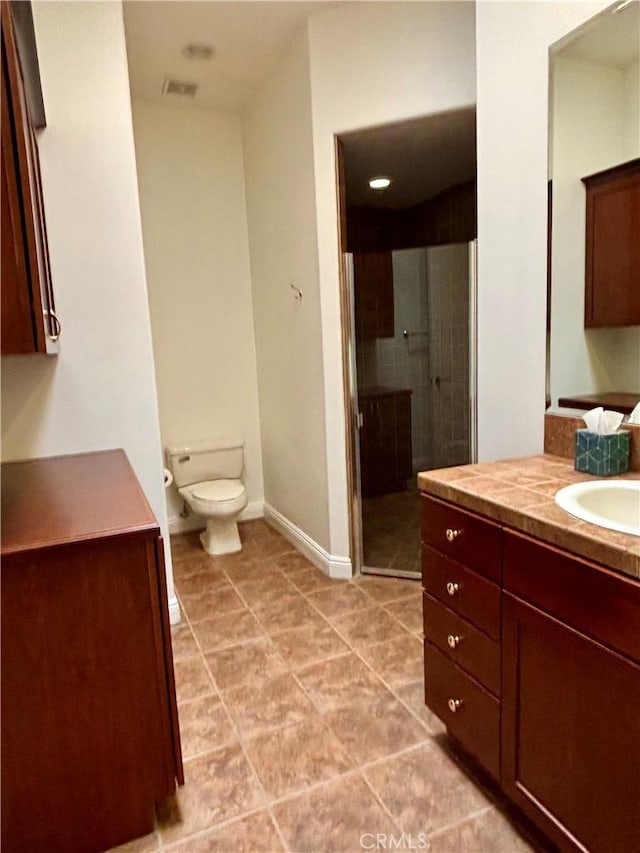 bathroom with tile patterned floors, vanity, toilet, and a shower with door