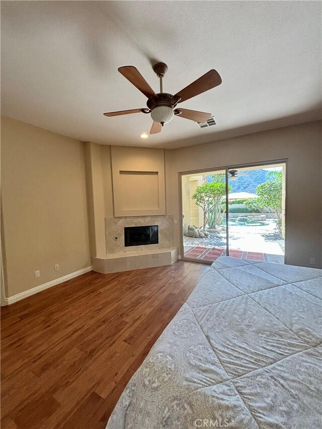 living room with ceiling fan, wood-type flooring, and a high end fireplace