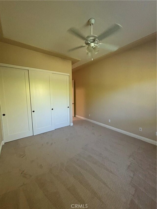 unfurnished bedroom with ceiling fan, a closet, and light carpet