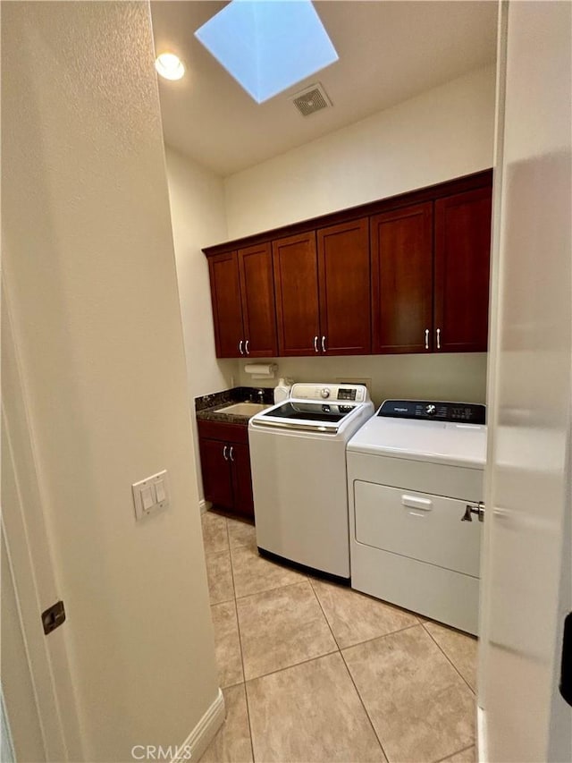 washroom with sink, cabinets, a skylight, light tile patterned floors, and washer and clothes dryer