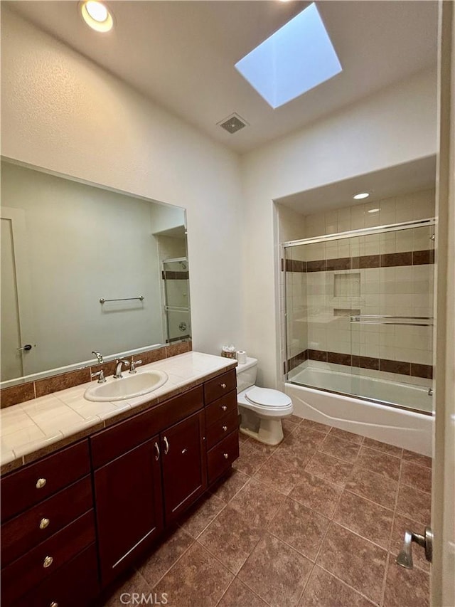 full bathroom featuring vanity, a skylight, enclosed tub / shower combo, and toilet