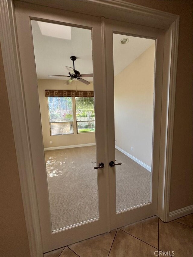 doorway with light tile patterned floors, ceiling fan, and french doors