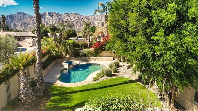 view of swimming pool with an in ground hot tub, a mountain view, and a lawn