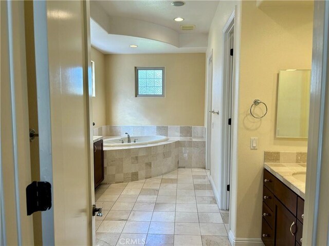 bathroom featuring tiled tub, tile patterned floors, and vanity