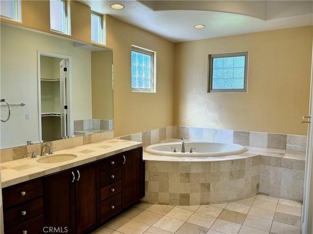 bathroom featuring vanity, tiled tub, and tile patterned flooring