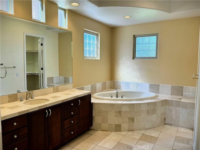 bathroom featuring tile patterned flooring, tiled tub, and vanity