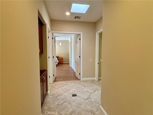 hallway featuring a skylight and light tile patterned floors