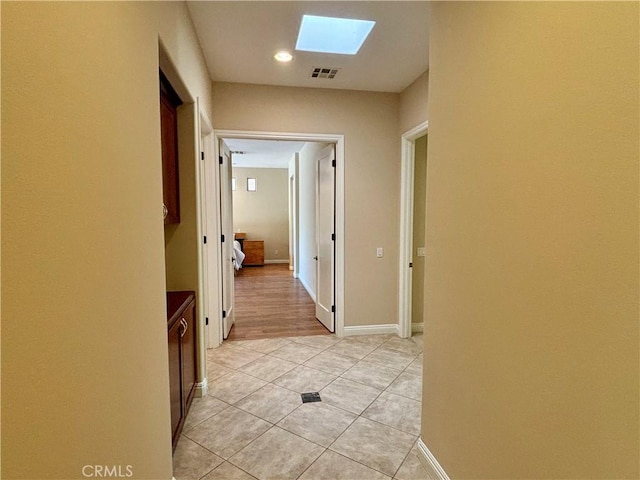 hall with light tile patterned floors and a skylight