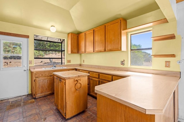 kitchen featuring lofted ceiling, a kitchen island, kitchen peninsula, and sink