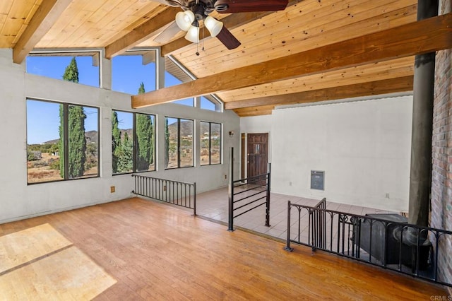 unfurnished room featuring vaulted ceiling with beams, wood-type flooring, a healthy amount of sunlight, and ceiling fan