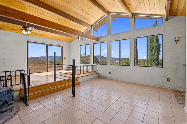 sunroom featuring a mountain view, vaulted ceiling with beams, a wood stove, and wood ceiling