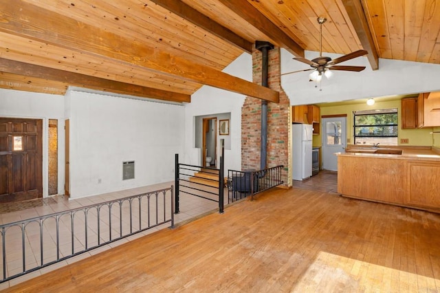 kitchen with beam ceiling, white fridge, light wood-type flooring, and a wood stove