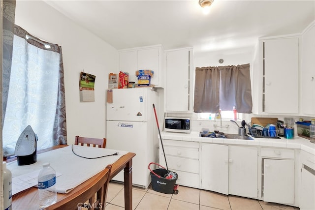 kitchen with tile countertops, sink, white cabinetry, and white appliances