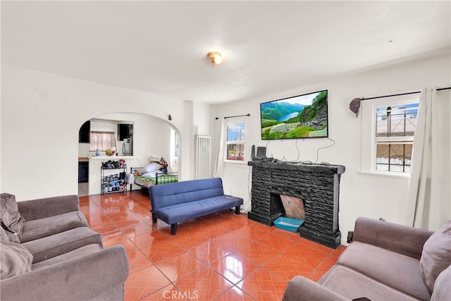 living room featuring a stone fireplace and tile patterned flooring