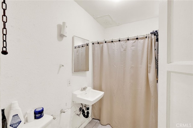 bathroom featuring toilet, curtained shower, and tile patterned floors