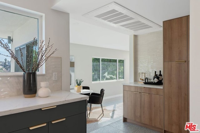 kitchen featuring tasteful backsplash and light stone counters