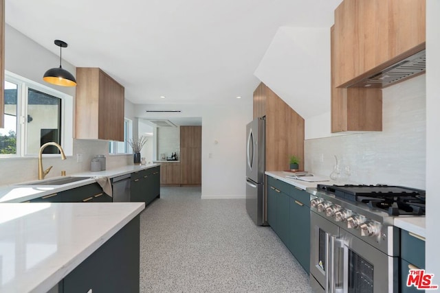 kitchen with tasteful backsplash, pendant lighting, sink, appliances with stainless steel finishes, and wall chimney exhaust hood