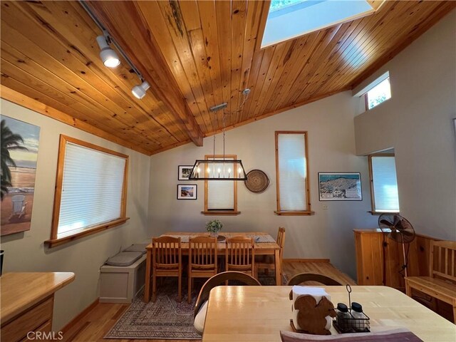 dining space with wooden ceiling, vaulted ceiling with skylight, and light hardwood / wood-style floors